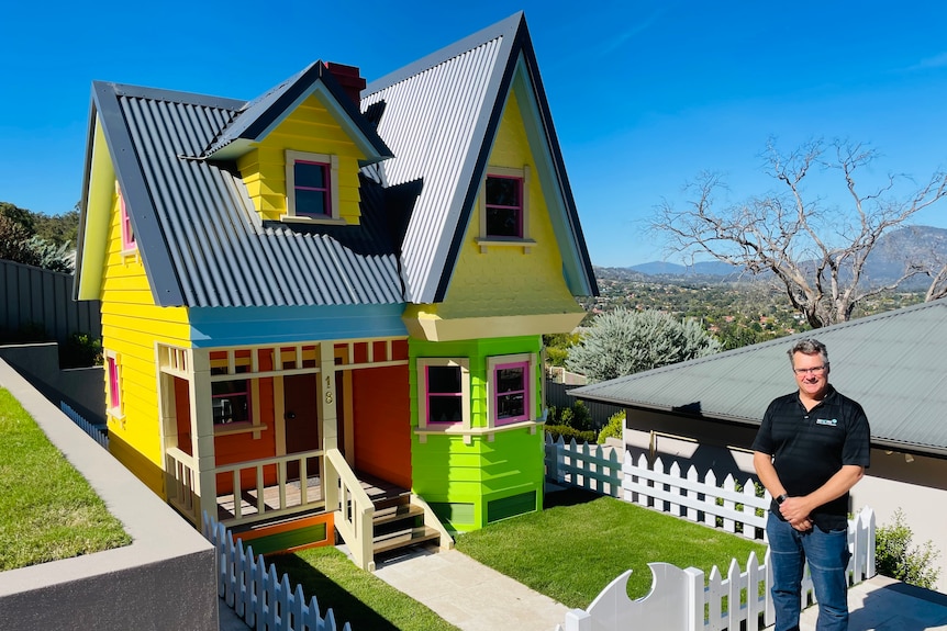 A man stands outside a massive cubby house, complete with its own front yard, overlooking suburban Canberra.