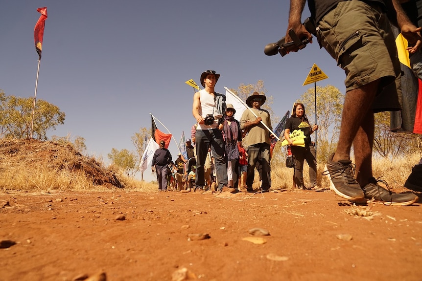 A group walks, some carry signs saying 'No Fracking'