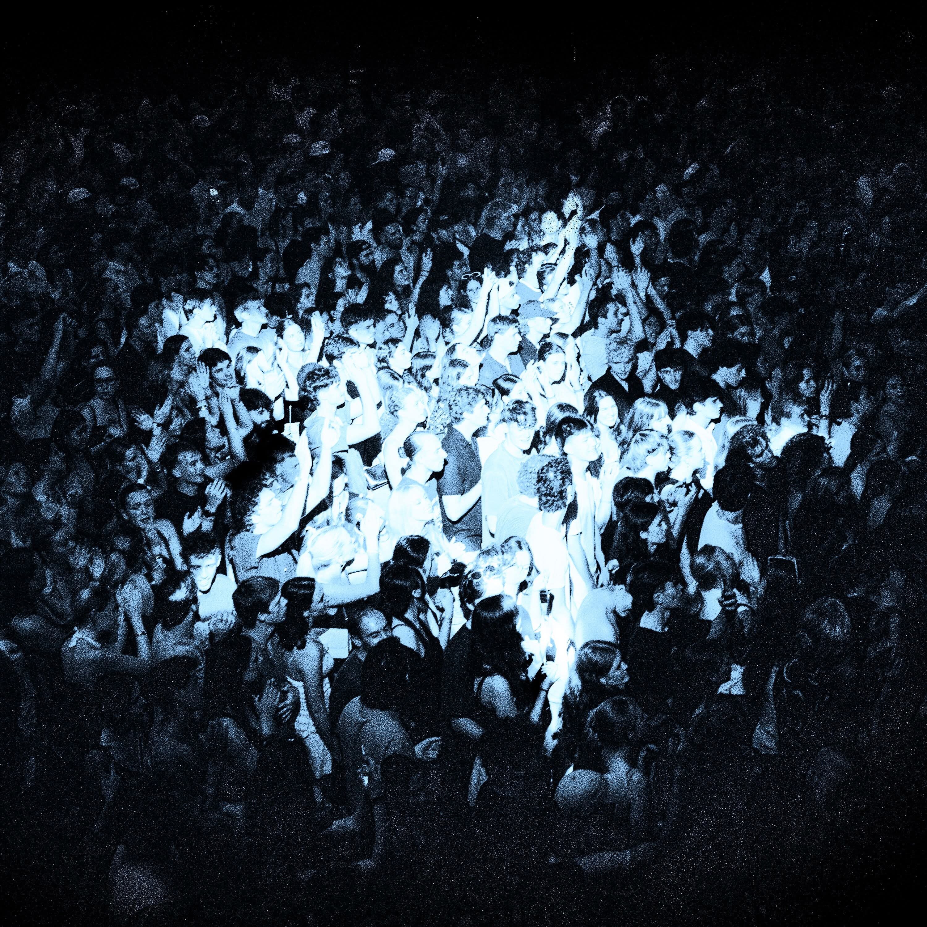 Photo of concert crowd with light in the shape of a star projected onto it.