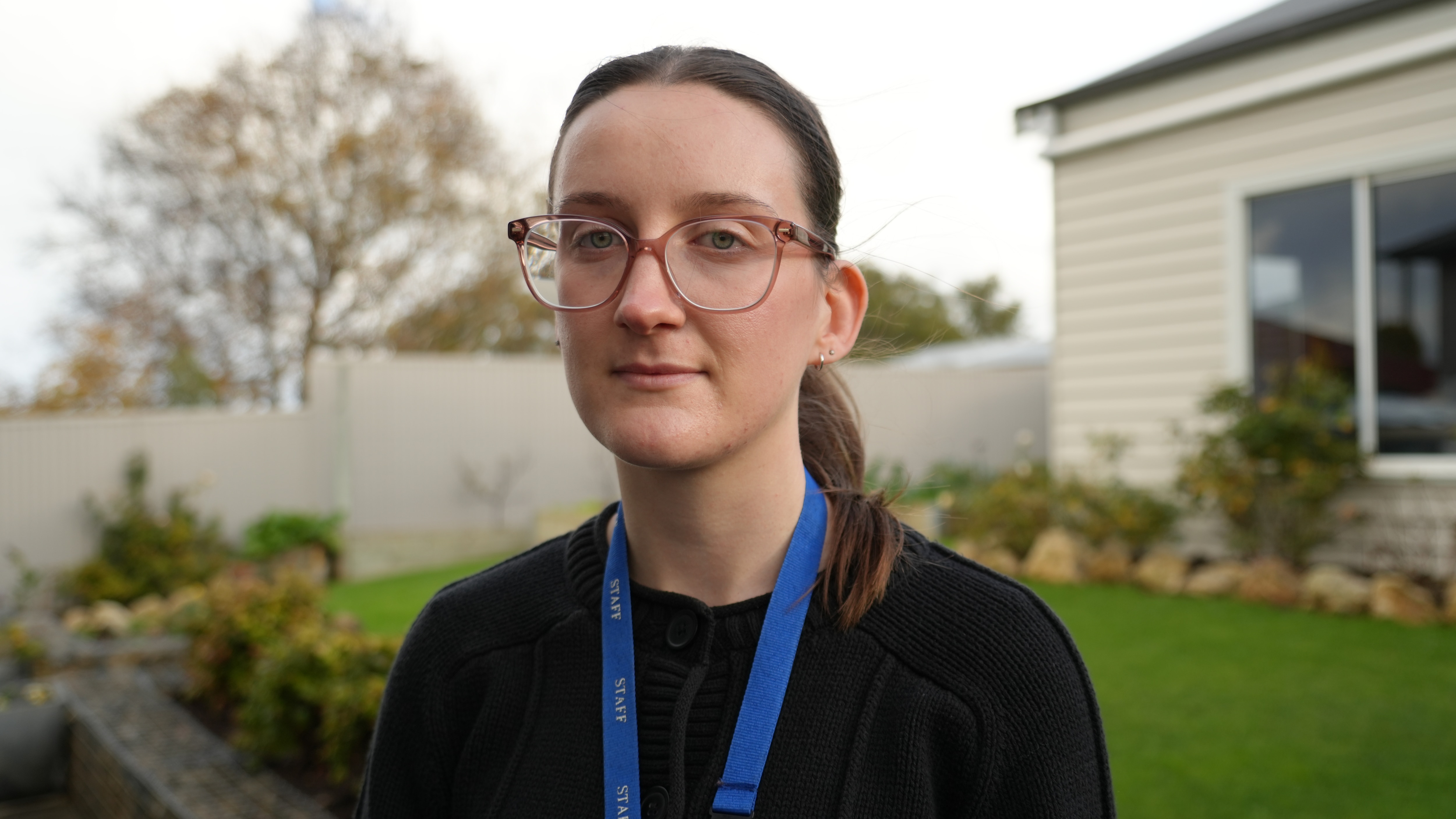 A woman with glasses and lanyard looking at the camera