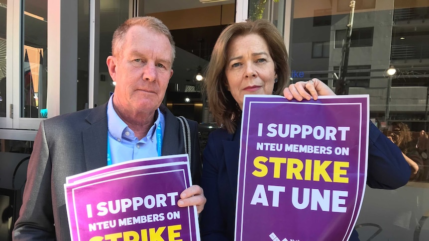 Union officials in front a cafe hold signs in support of a strike at the University of New England