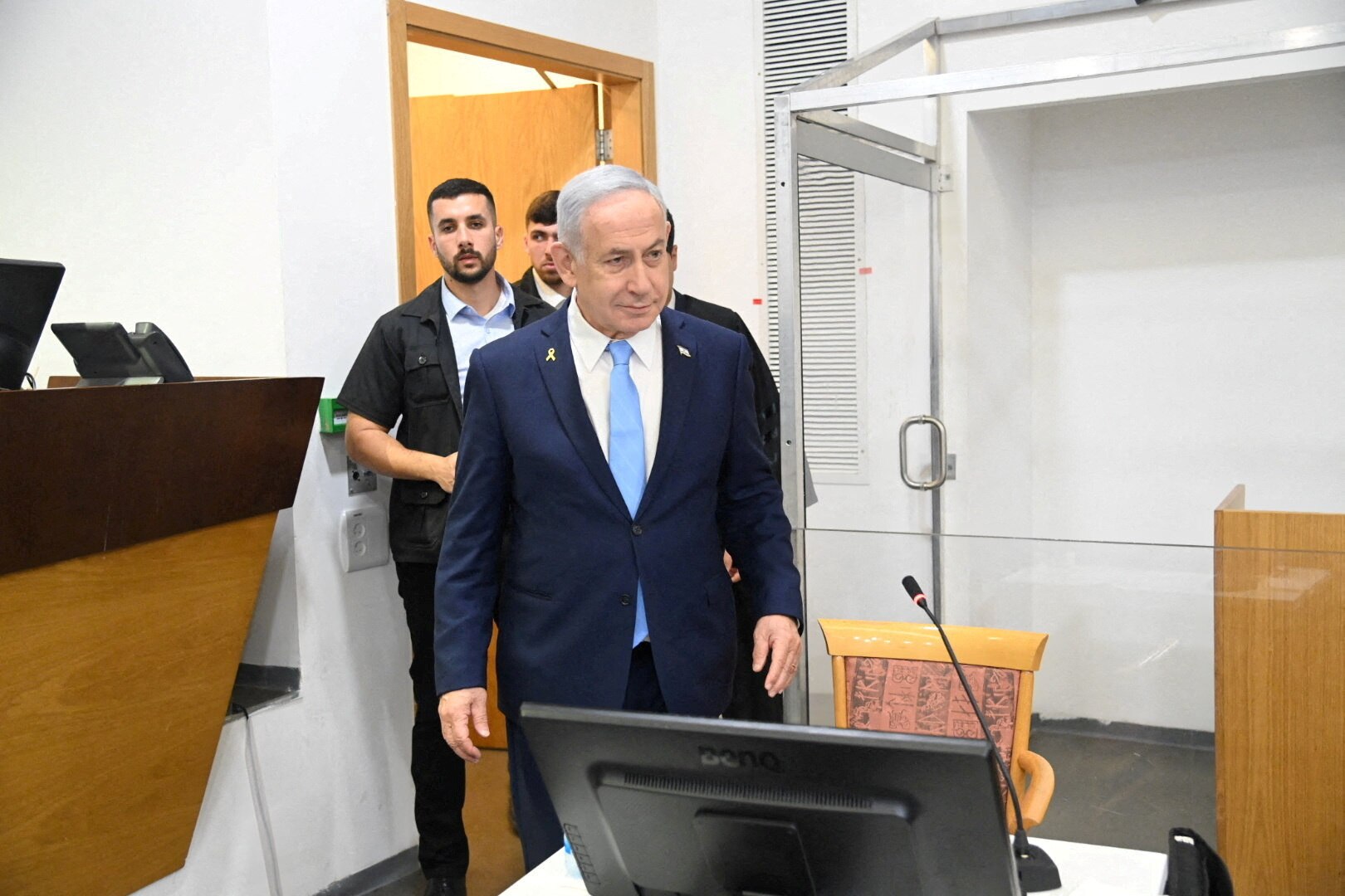 Benjamin Netanyahu grins as he walks into a courtroom to attend his trial.
