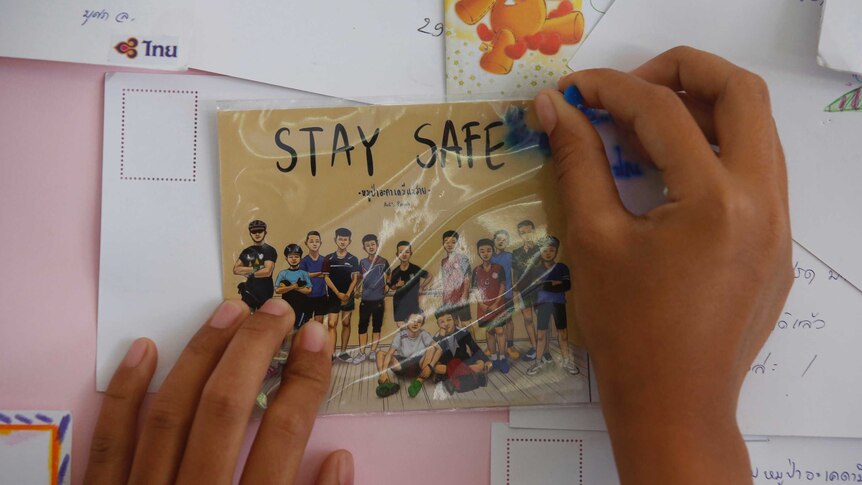 Seorang warga Thailand memasang kartu ucapan doa agar anak-anak tersebut selamat
