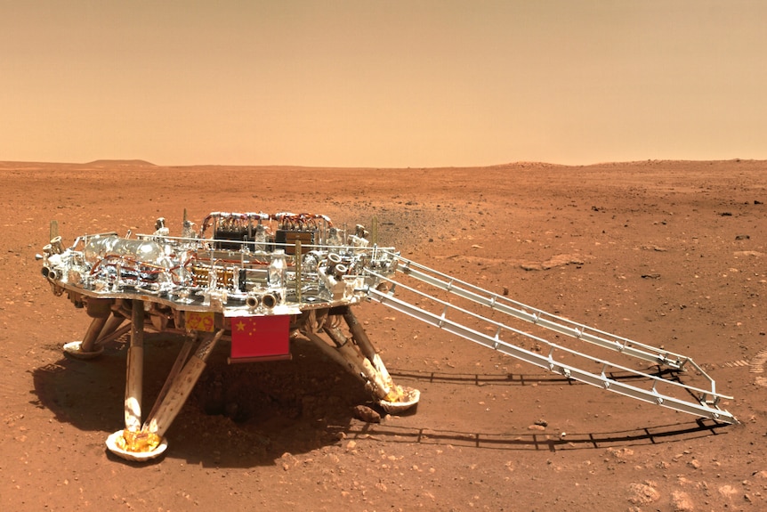 Chinese Mars rover Zhurong sits on the dusty ground bearing a Chinese flag.