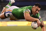 Nick Cotric is horizontal as he dives towards the try line with the ball in one hand. A Souths opponent trails behind him