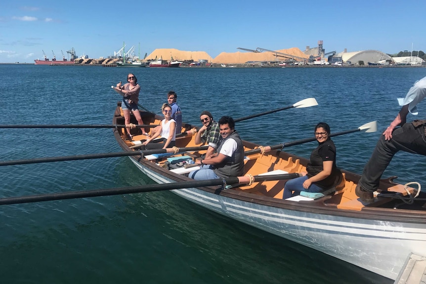 Seven young people in a row boat on the water