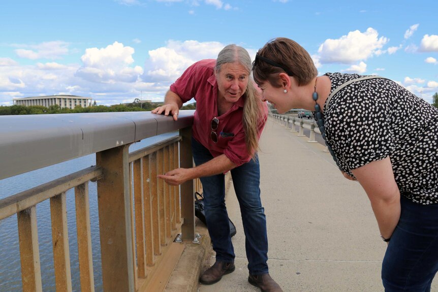 Dave Rowell from ANU and Madeline Cooper examine the spider webs that remain on the Commonwealth Avenue bridge.