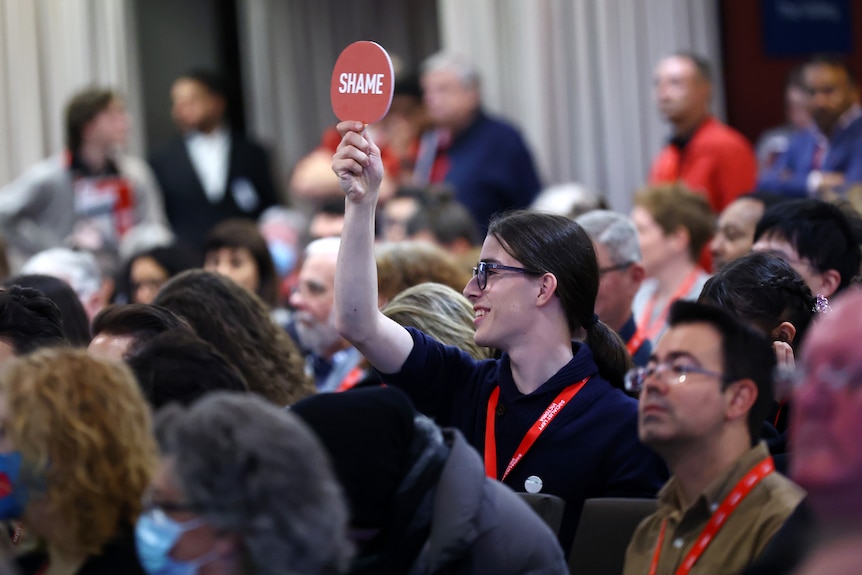 An observer is seen holding up a sign during the 2024 Victorian Labor state conference 