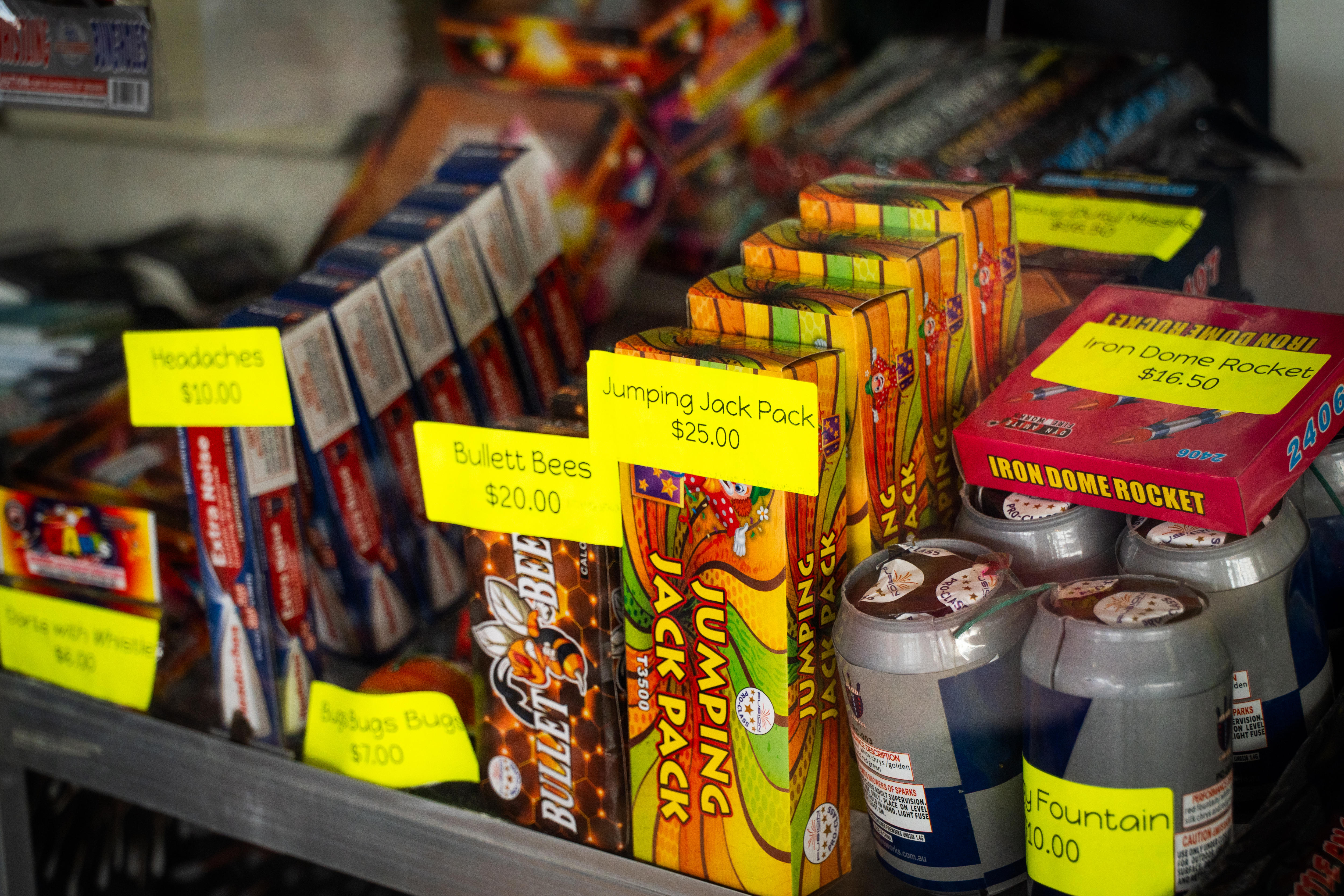An array of small, brightly coloured boxes, holding fireworks, arranged on a store shelf. 