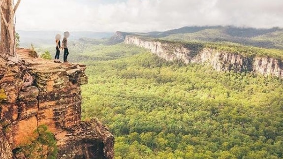 A photo of a couple standing on the edge of a sandstone cliff posted on instagram