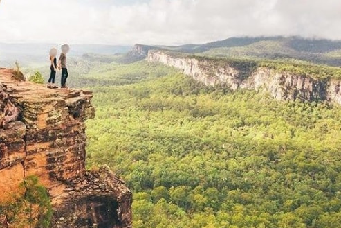 A photo of a couple standing on the edge of a sandstone cliff posted on instagram