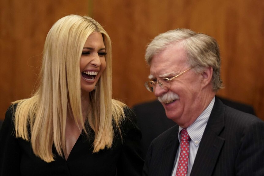 John Bolton and Ivanka Trump laughing together in a board room