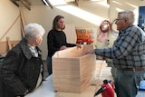 Three coffin club members around a table with a coffin.