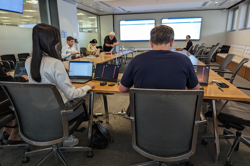 Journalists set up their laptops in the lock-up room.