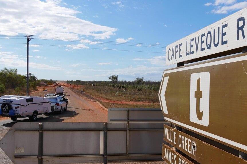 Image of caravans pulling onto a road, with a road sign in the immediate foreground.