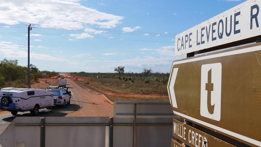 Image of caravans pulling onto a road, with a road sign in the immediate foreground.