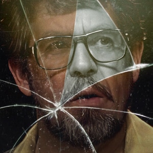 Close-up of Rolf Harris face in glasses, partially covered by a large crack, with a contrasting color effect.