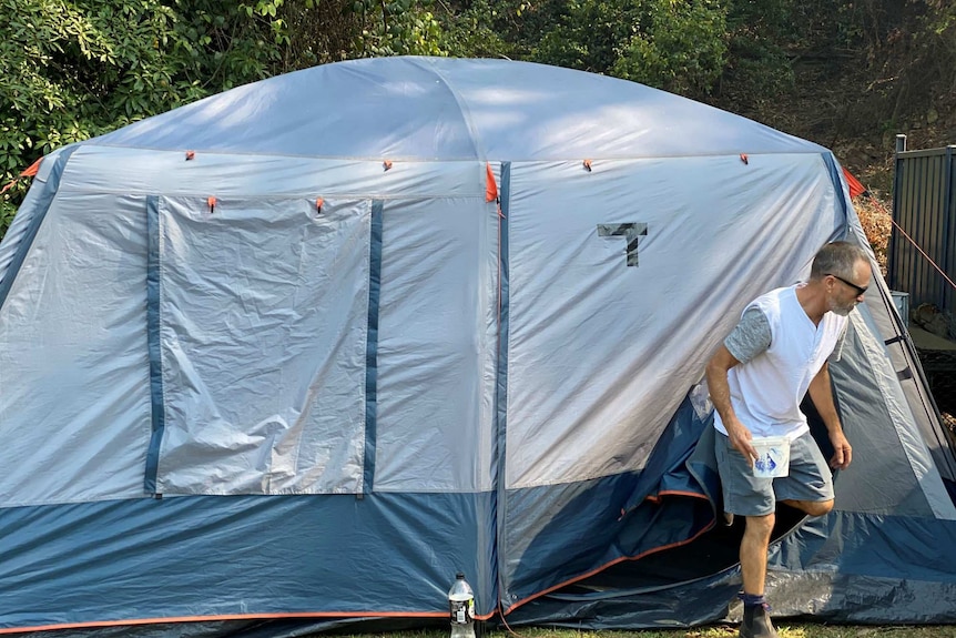 Roy Sayer emerges from a tent which is temporary accommodation after his home burnt down.