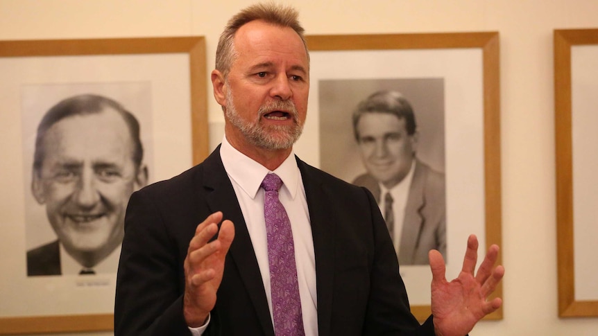 Nigel Scullion gestures with his hands while speaking.