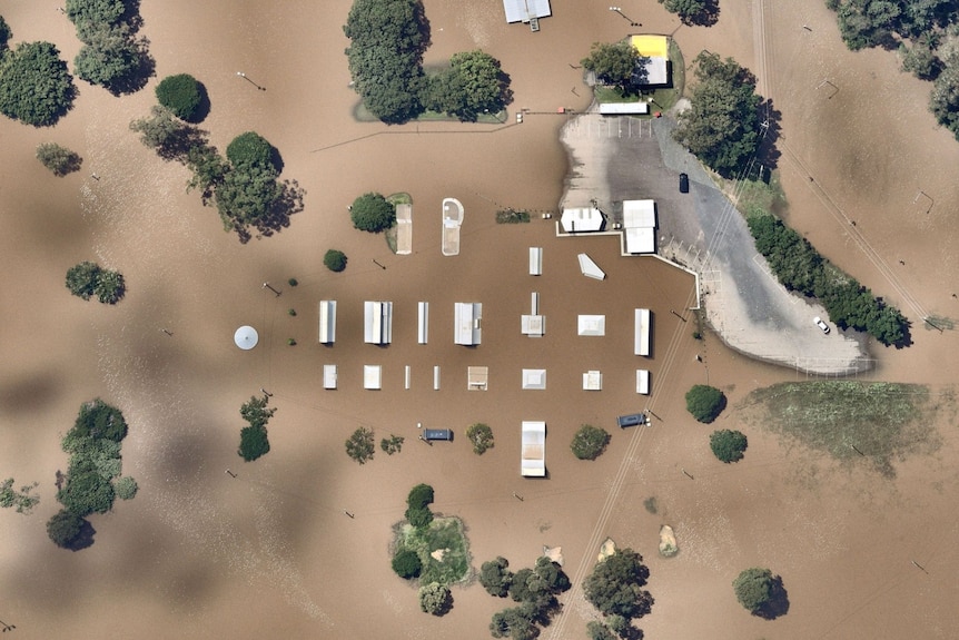 The tops of a skate park poke out from beneath muddy floodwaters, as seen from above.