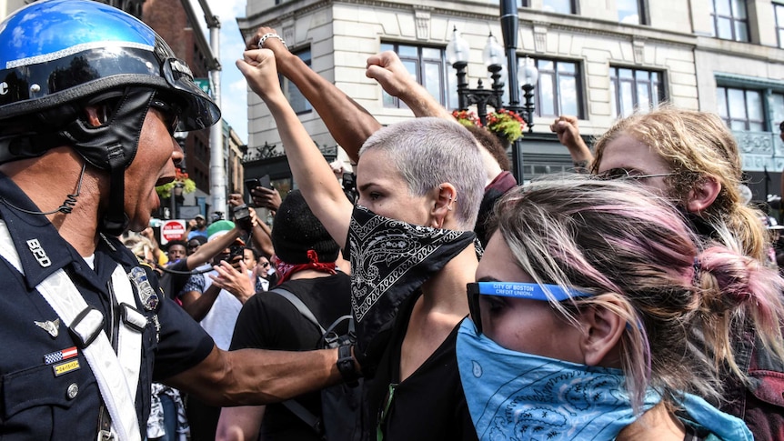 Riot police restrain counter-protesters with bandanas across their faces in Boston.