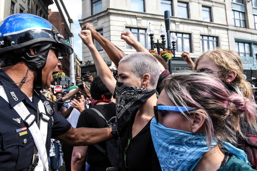 Riot police restrain counter-protesters with bandanas across their faces in Boston.