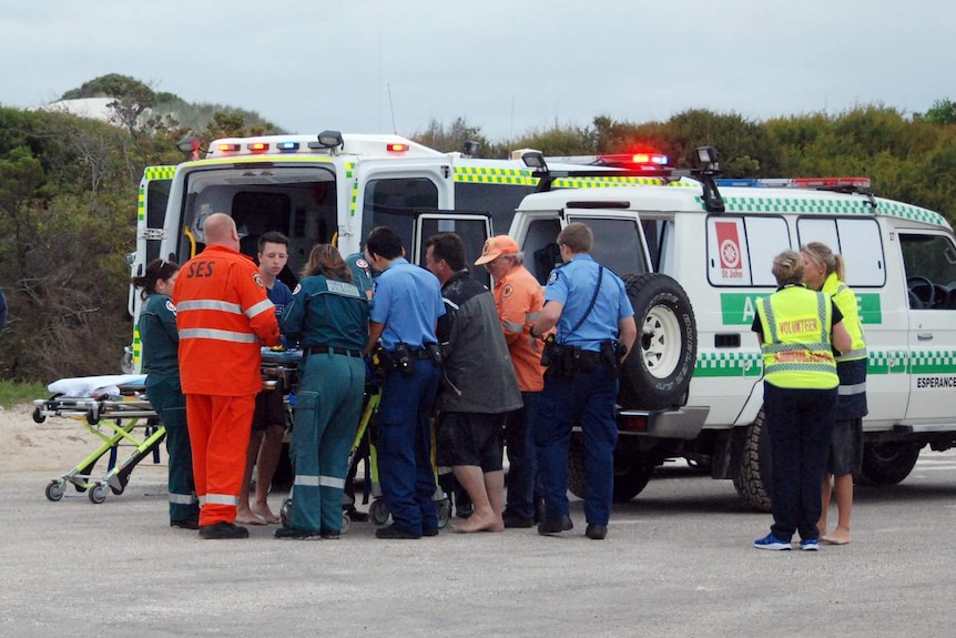 Emergency service workers surround an ambulance.