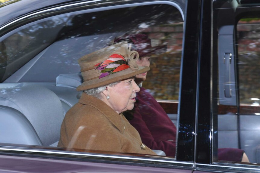 Queen Elizabeth II can be seen through the window of a car with another woman beside her