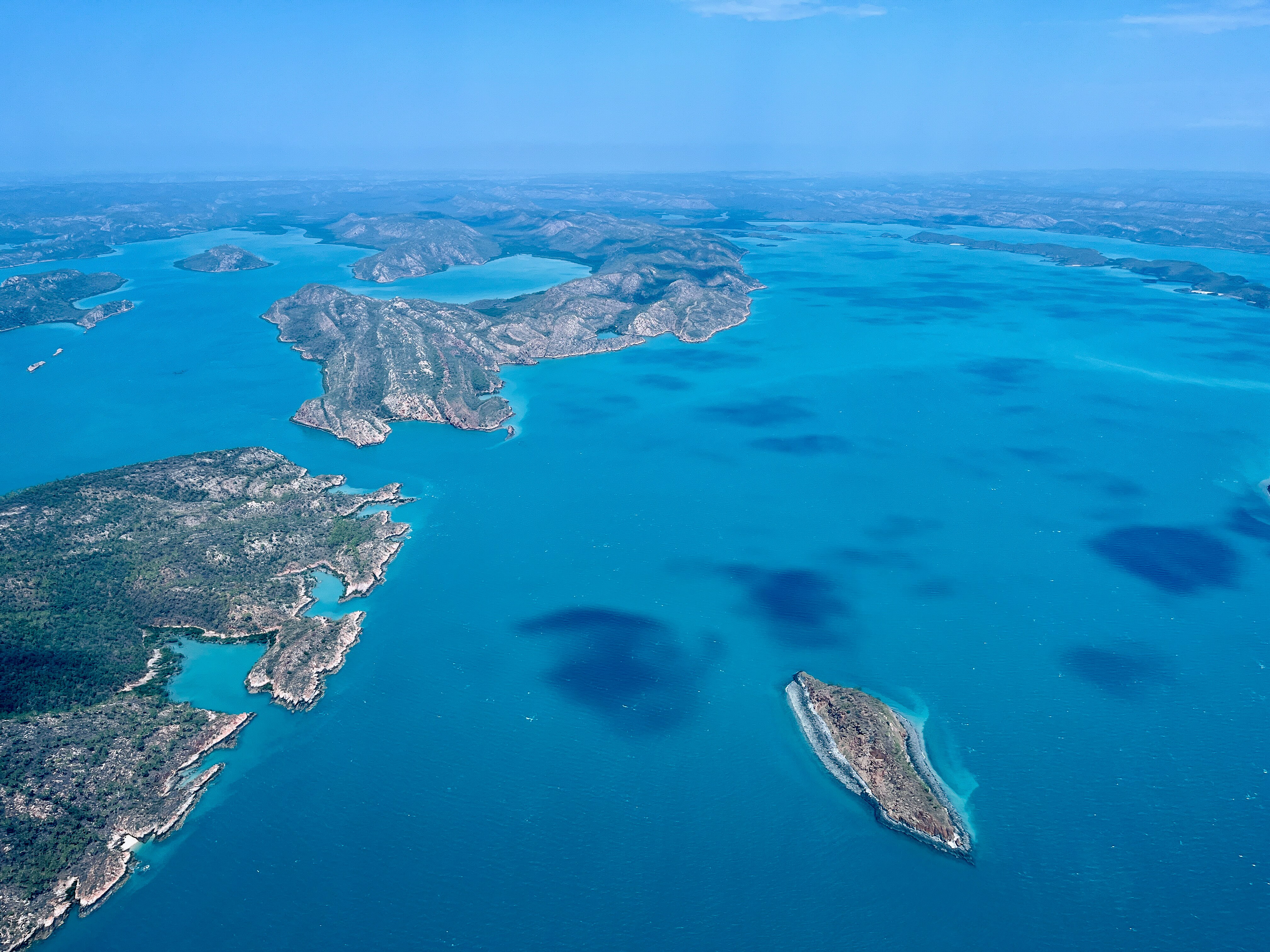 An aerial view shows a group of islands dotted against a bright turquoise sea