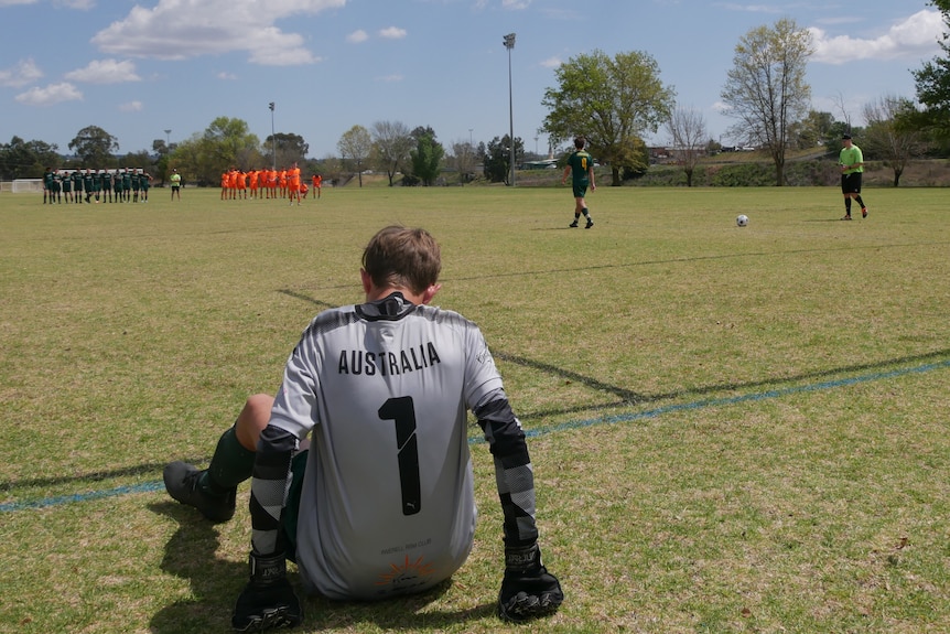 A goal keeper sits and watches on a penalty shootout in front of him.