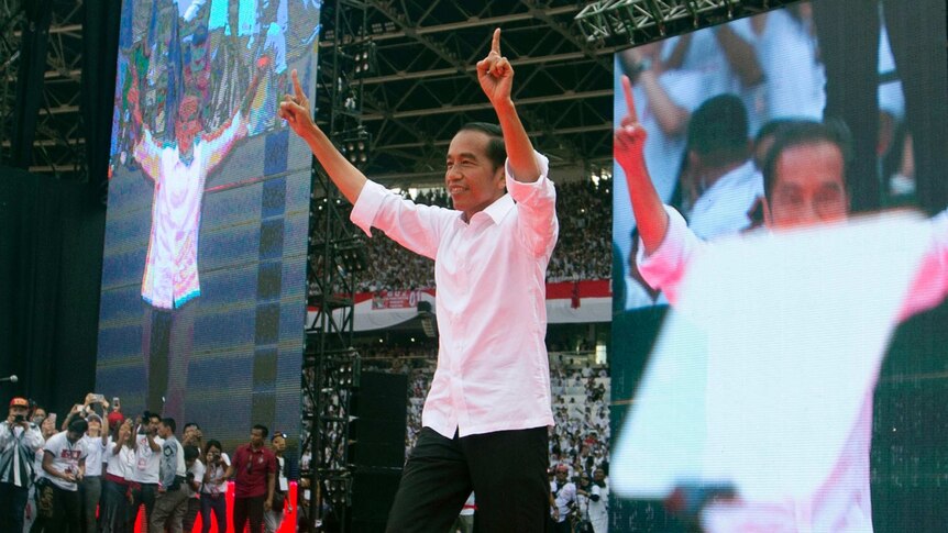 Indonesia president Joko Widodo points his fingers in the air and appears to dance on a stage.
