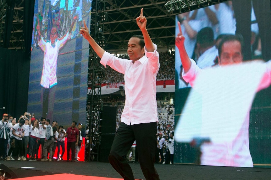 Indonesia president Joko Widodo points his fingers in the air and appears to dance on a stage.