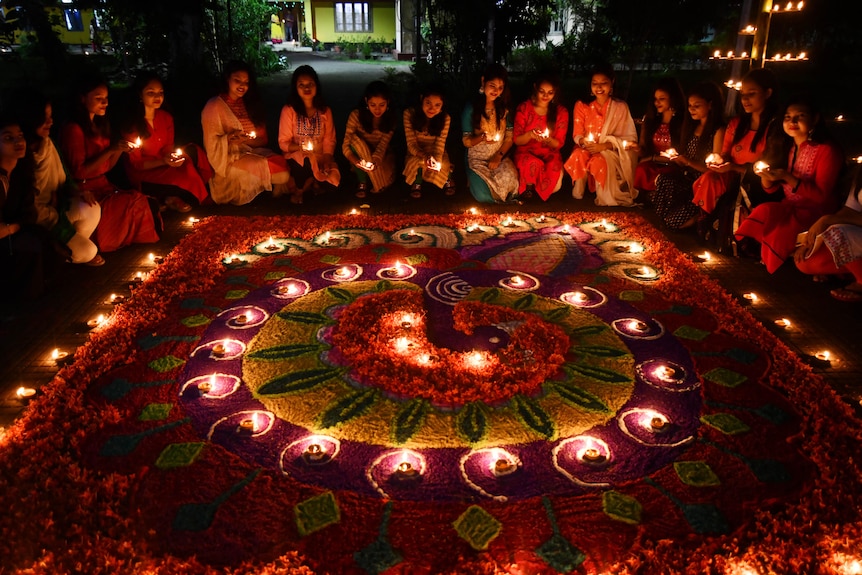 Girls light lamps at night during Diwali in India.