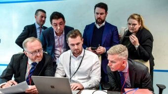 AFP officers sit with the ABC Legal team and an IT Specialist all looking at a laptop.