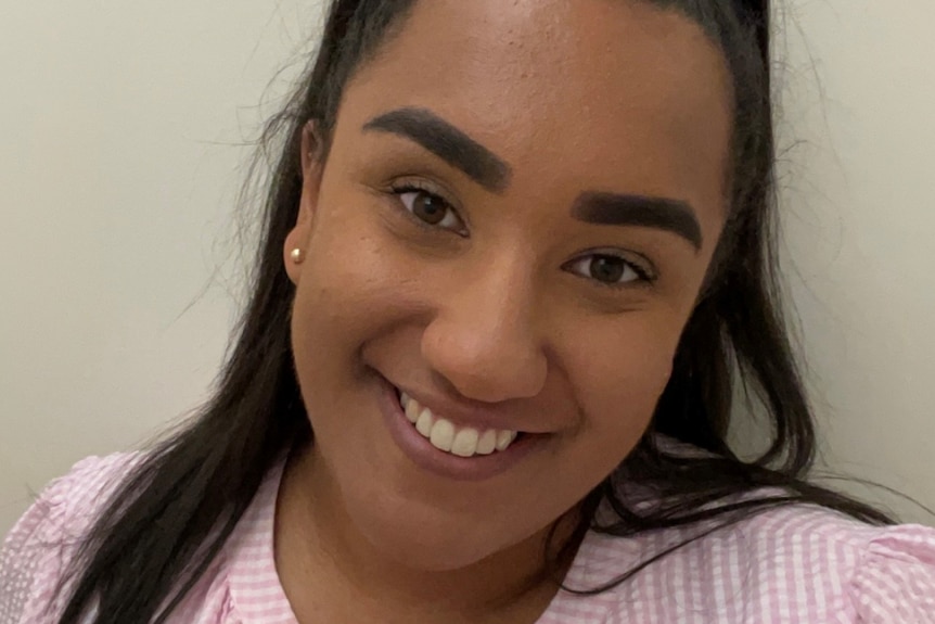 Young woman with dark hair in a ponytail, pink checked shirt