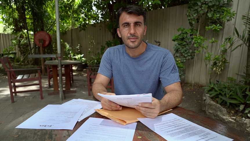 Farhad Rahmati sits at a table with documents in front of him