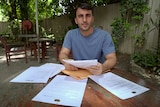 Farhad Rahmati sits at a table with documents in front of him