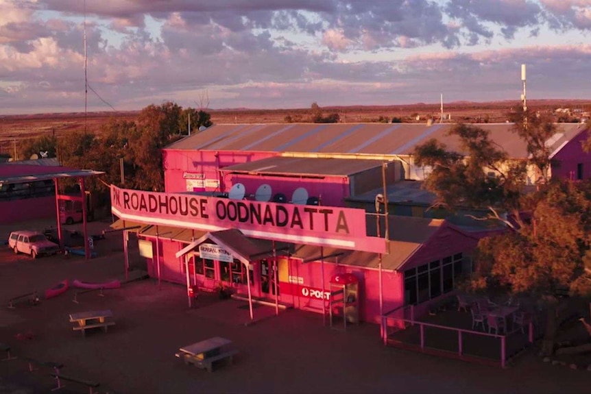 An aerial photo is taken from a drone as a pink roadhouse (READS: Roadhouse Oodnadatta) is looked down on the outback sunset.