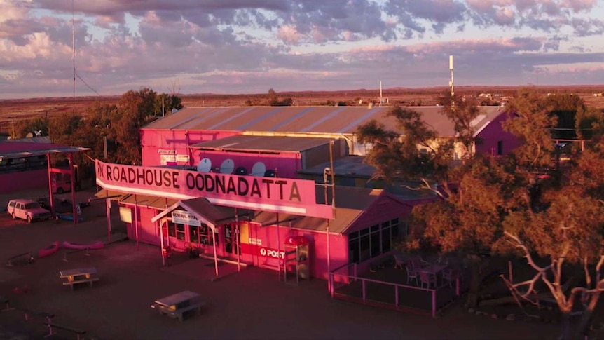An aerial photo is taken from a drone as a pink roadhouse (READS: Roadhouse Oodnadatta) is looked down on the outback sunset.