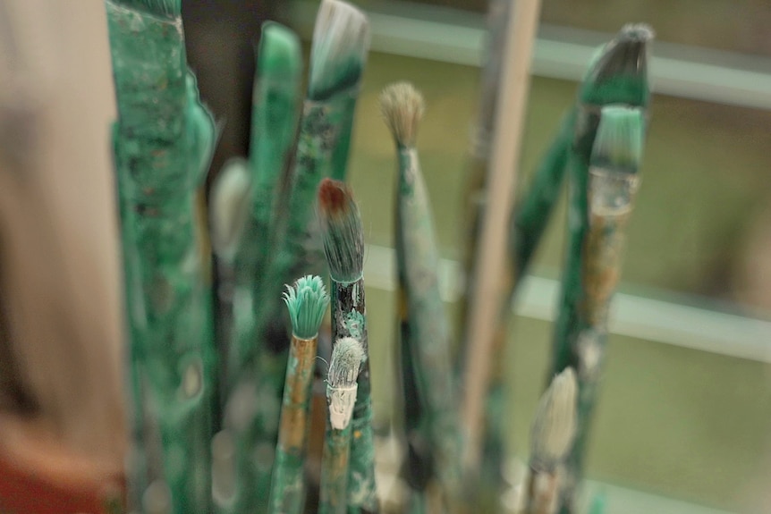 Paint brushes with green paint on them