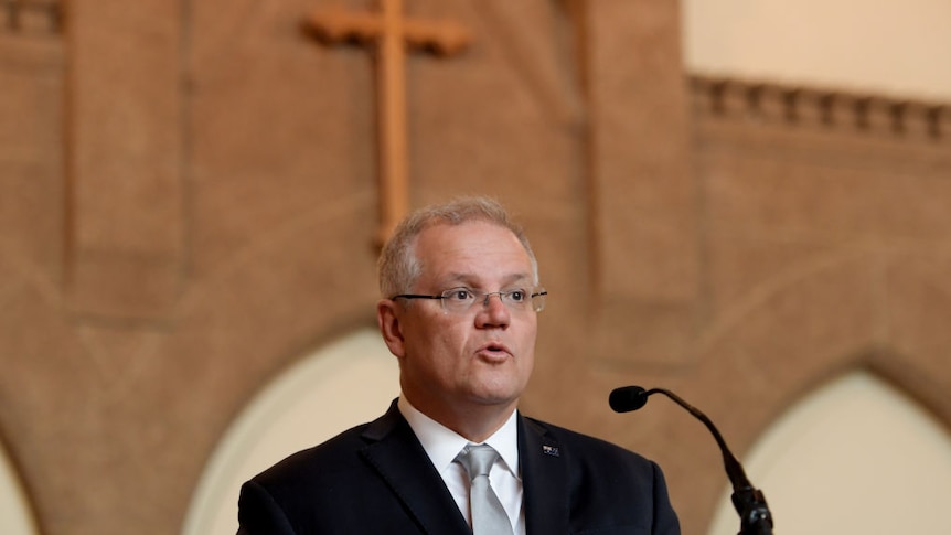 scott morrison speaking into microphone in church setting with cross behind