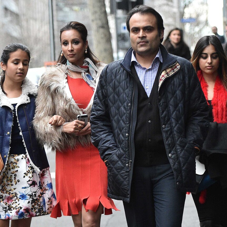 Panjak and Radhika Oswal walk along the footpath towards a camera with their two daughters.