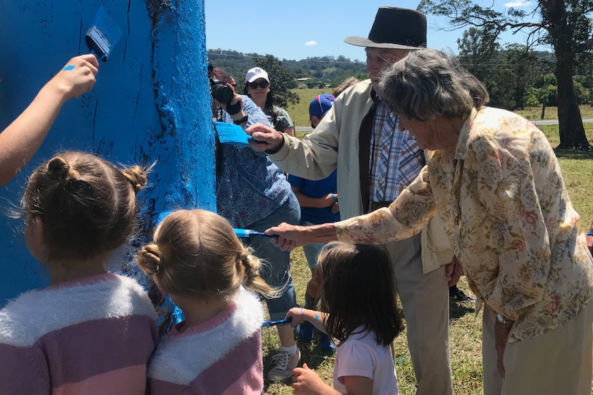 Adults and children painting the trees.