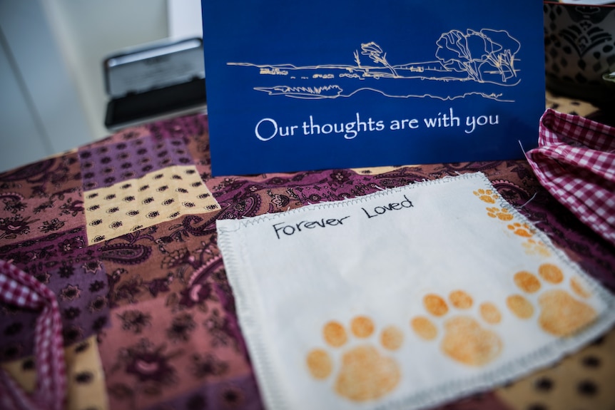 A purple fabric with the words 'forever loved' and two paw prints stitched on it.