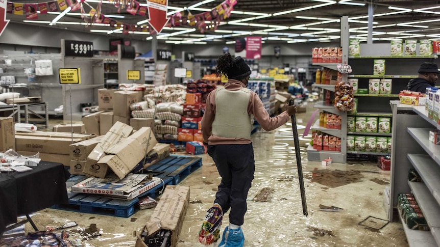 A female South Africa police officer walking the damaged in store after looted in Vosloorus.