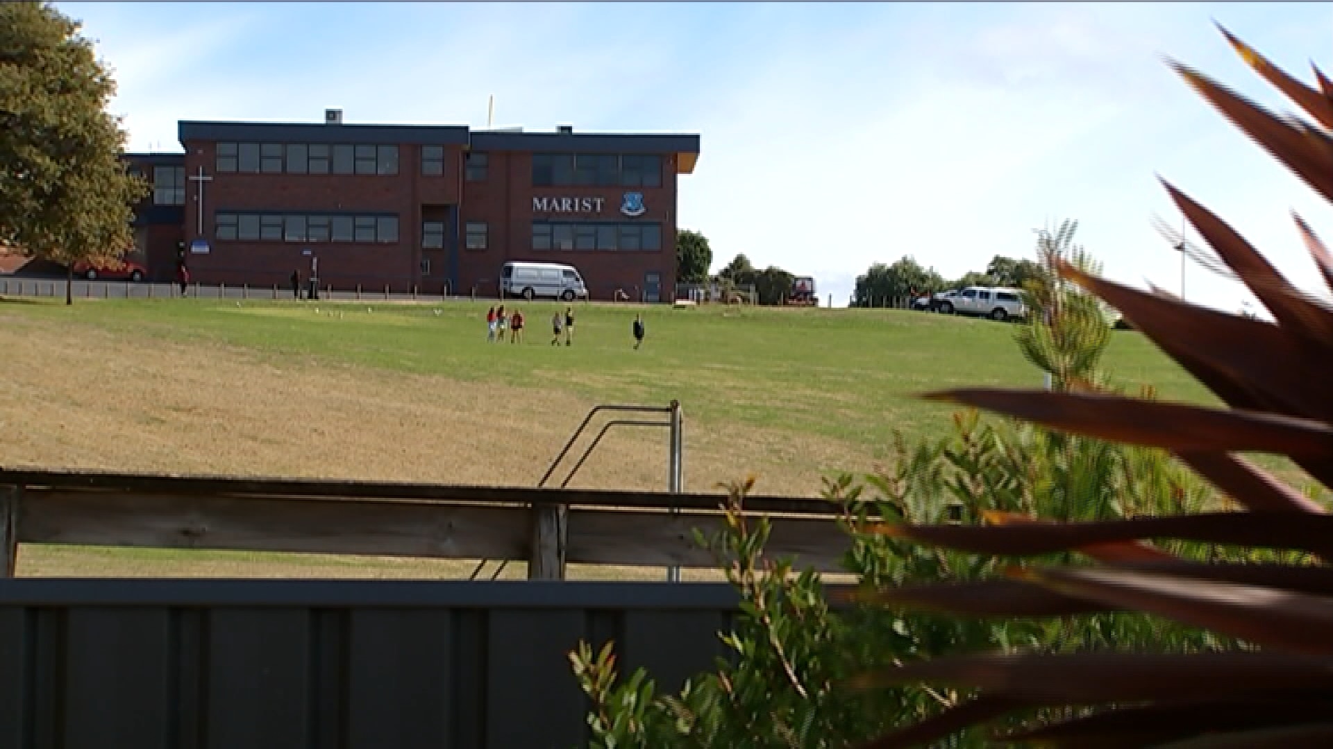 A school oval with the Marist Regional College emblem on a building wall.