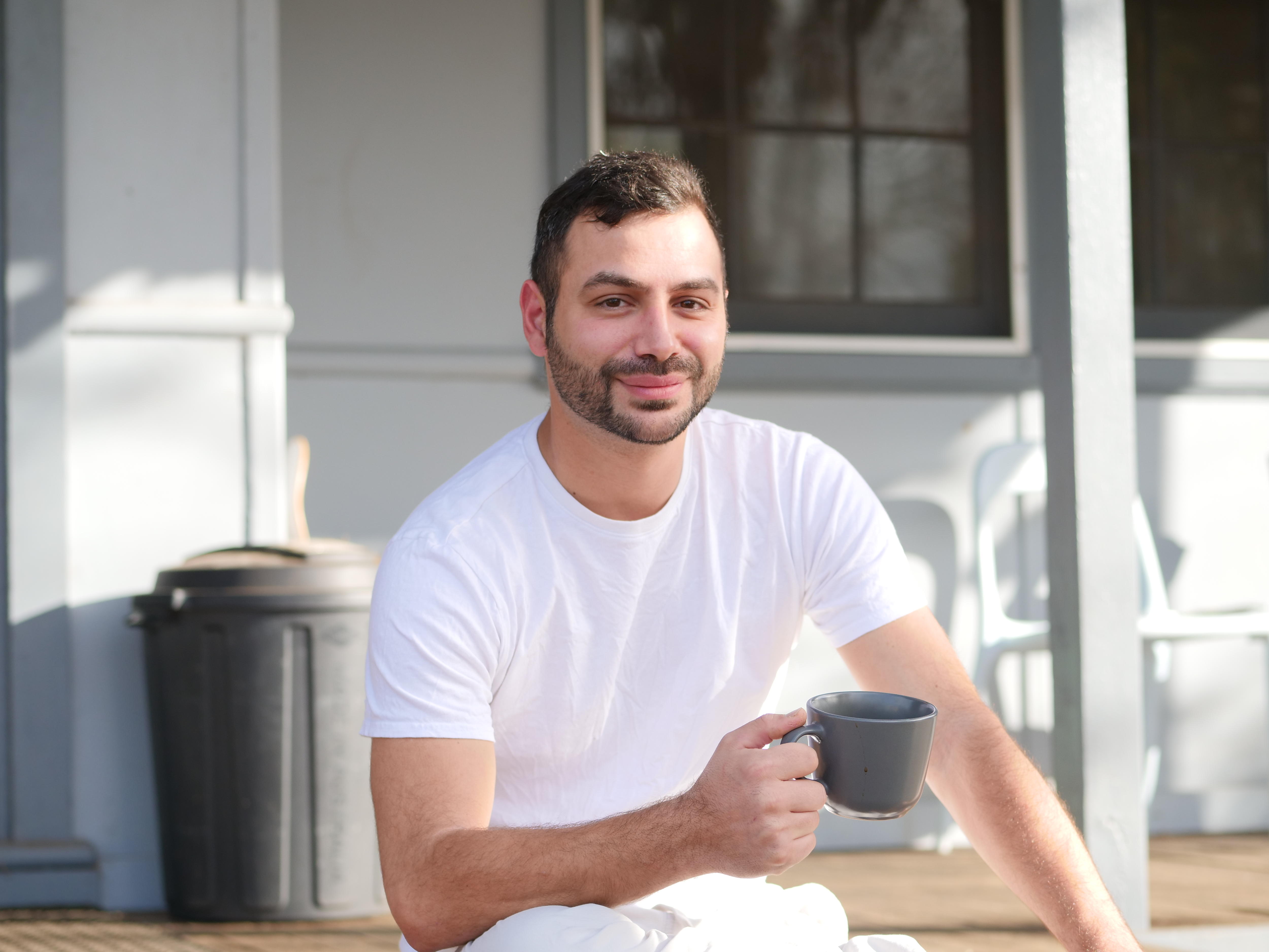 A bacpacker sits on a step with a coffee