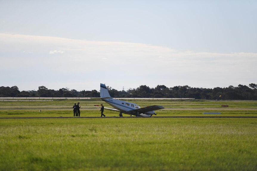 A plane landed on its nose on the runway with several people around it.
