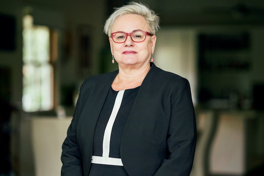 A woman wearing red glasses and a black jacket.