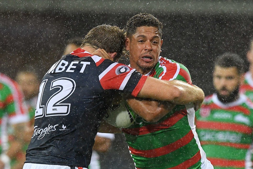 Dane Gagai holds the ball in the rain, as he tries to beat the defence of Mitchell Aubusson.